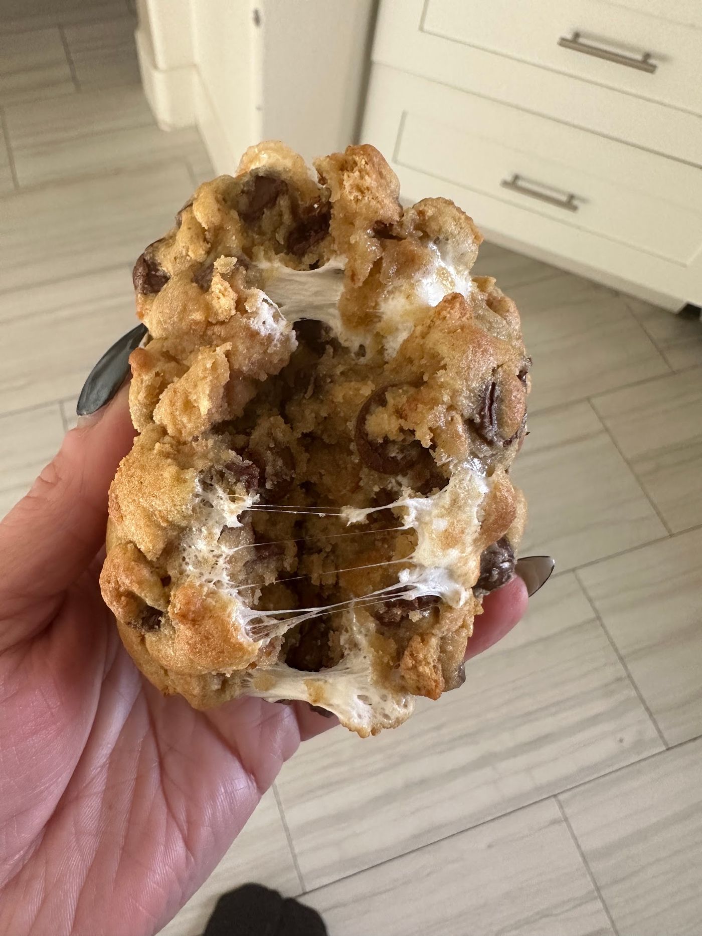 A S'mores cookie pulled apart with the marshmallow stretching